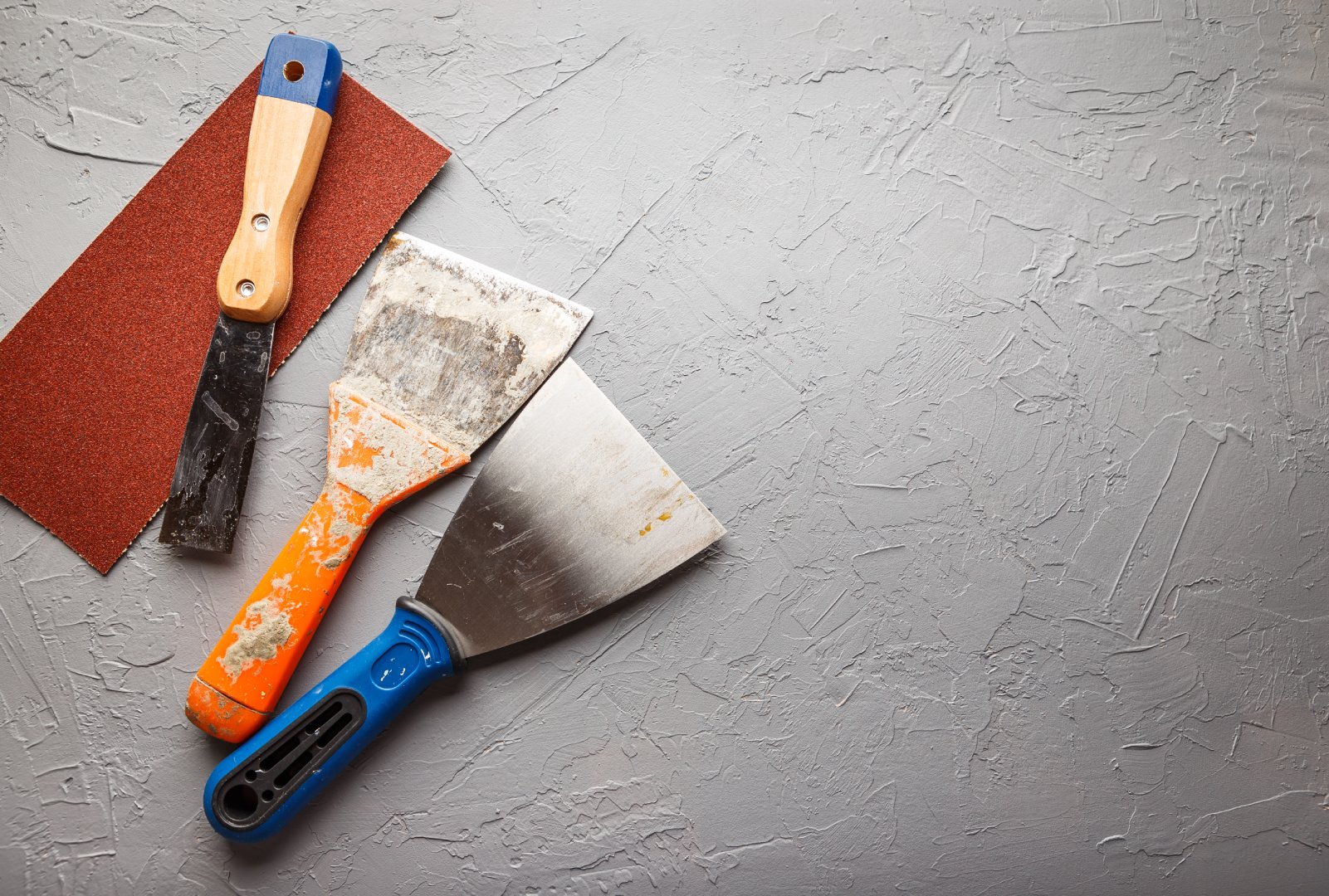 Construction tools - brushes, rollers, spatulas and sandpaper on a concrete background
